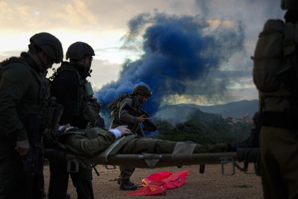 Soldados israelíes llevan a un compañero suyo en una camilla hacia un helicóptero durante un ejercicio de evacuación de heridos en el norte de Israel. Soldados israelíes llevan a un compañero suyo en una camilla hacia un helicóptero durante un ejercicio de evacuación de heridos en el norte de Israel. - Sputnik Mundo