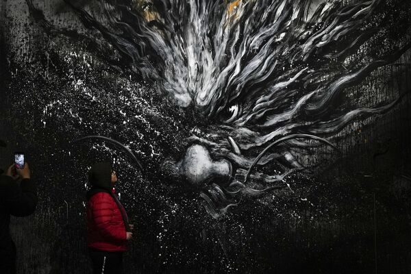 Una mujer posa para una foto junto a la imagen de un dragón en Pekín. Una mujer posa para una foto junto a la imagen de un dragón en Pekín. - Sputnik Mundo