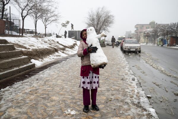 Una niña con un muñeco de nieve en una calle de Kabul, Afganistán. Una niña con un muñeco de nieve en una calle de Kabul, Afganistán. - Sputnik Mundo
