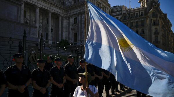 Una mujer sostiene una bandera argentina frente a una línea de policías durante una huelga nacional contra el Gobierno de Javier Milei en Buenos Aires el 24 de enero de 2024 - Sputnik Mundo