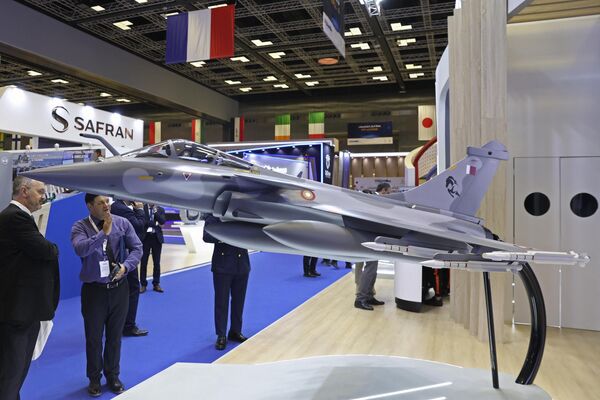 Cada edición del acontecimiento ofrece amplias oportunidades comerciales en forma de Memorandos de Entendimiento y acuerdos reales que se cierran durante los tres días del evento.En la foto: visitantes observan una maqueta del caza de producción francesa Rafale. - Sputnik Mundo