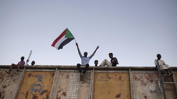 Un manifestante ondea una bandera nacional sudanesa durante una sentada en la Plaza de las Fuerzas Armadas en Jartum, Sudán, el 27 de abril de 2019 - Sputnik Mundo