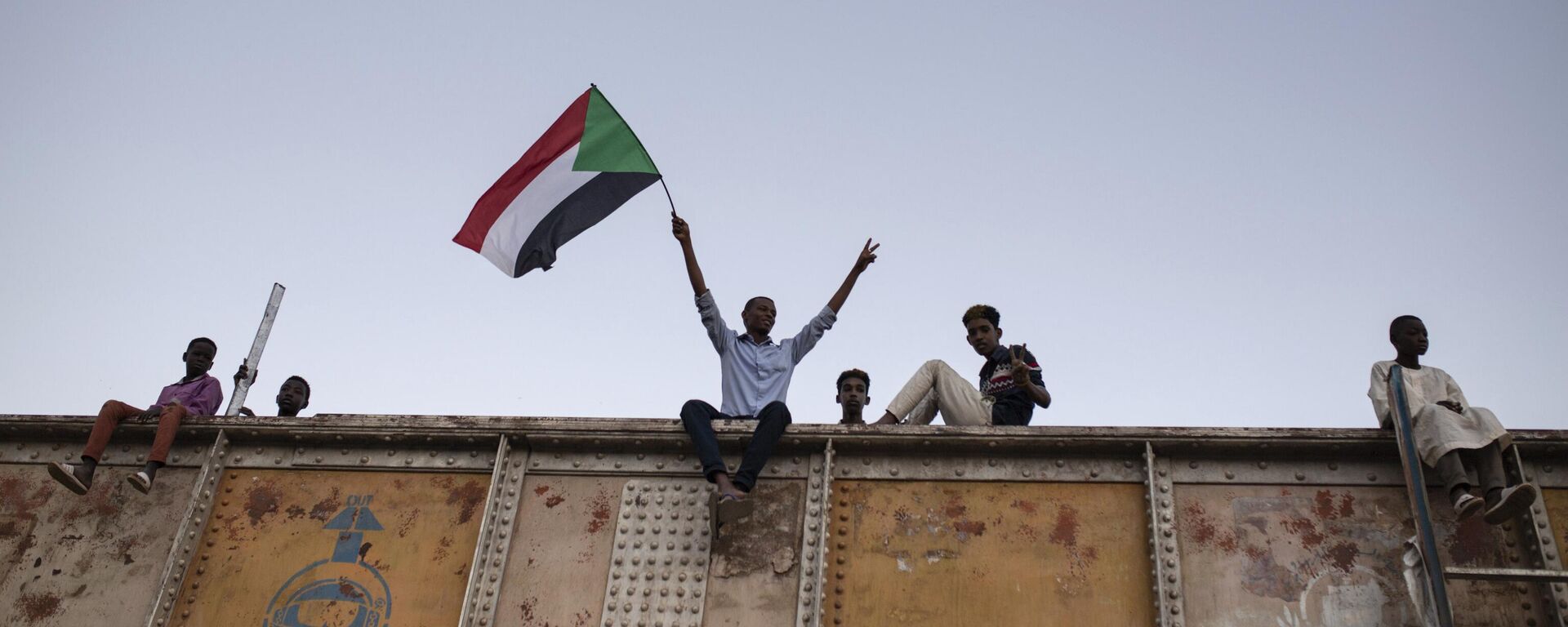 Un manifestante ondea una bandera nacional sudanesa durante una sentada en la Plaza de las Fuerzas Armadas en Jartum, Sudán, el 27 de abril de 2019 - Sputnik Mundo, 1920, 16.12.2024