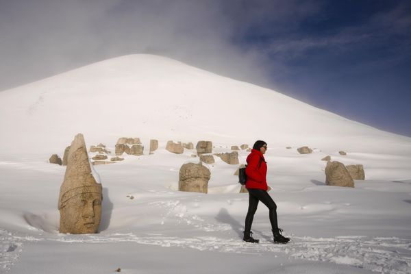 Las estatuas de la tumba del rey Antíoco se encuentran en el actual sureste de Turquía, cerca de la ciudad de Adiyaman. Forman parte de un complejo de templos y tumbas que el rey Antíoco I de Comagene construyó como monumento a sí mismo. En la foto: una mujer caminando junto a una de las antiguas estatuas de la tumba del rey Antíoco tras una nevada en la cima del monte Nemrut. - Sputnik Mundo