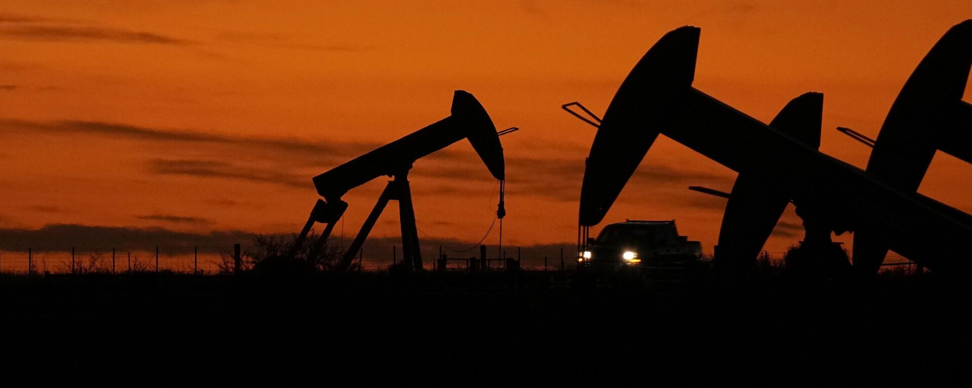 Un camión pasa junto a gatos de bombeo de petróleo al atardecer cerca de Karnes City, Texas, el 1 de noviembre de 2023. - Sputnik Mundo, 1920, 11.06.2024