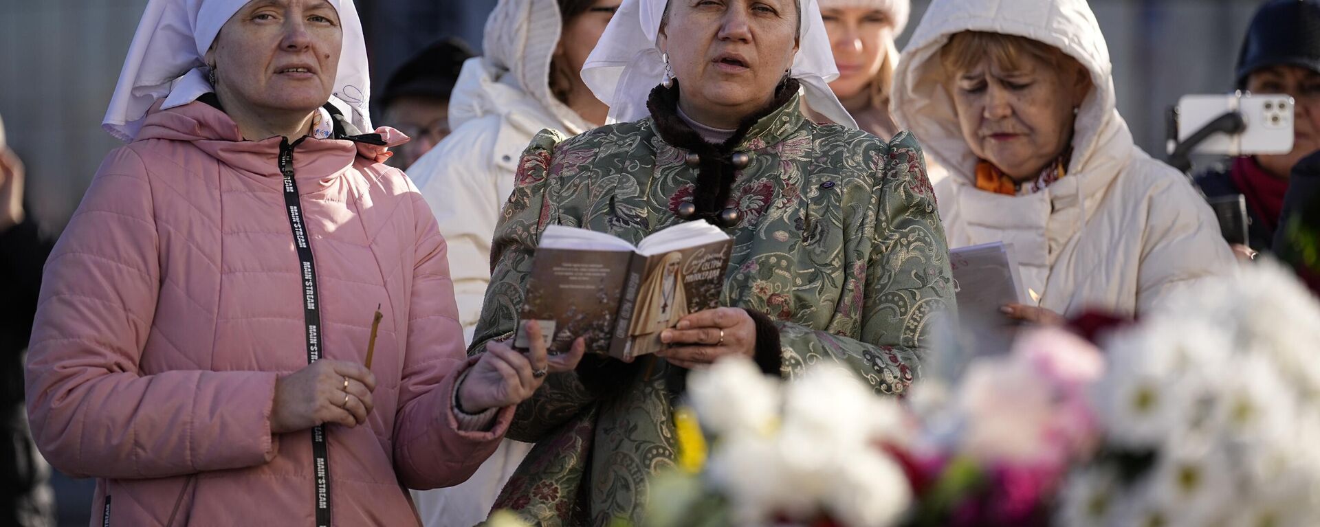 Mujeres rezan cerca del Ayuntamiento de Crocus en el extremo occidental de Moscú, Rusia, el lunes 25 de marzo de 2024, tras el ataque a la sala de conciertos Crocus City Call  - Sputnik Mundo, 1920, 25.03.2024