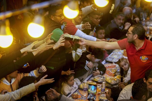 Sólo se permite comer y beber antes del amanecer y después del anochecer. Durante el Ramadán, los musulmanes deben dar generosamente, en forma de sadaqah (donaciones voluntarias) y zakat (limosna obligatoria).En la foto: un voluntario distribuye comida gratuita durante el iftar en El Cairo, Egipto. - Sputnik Mundo