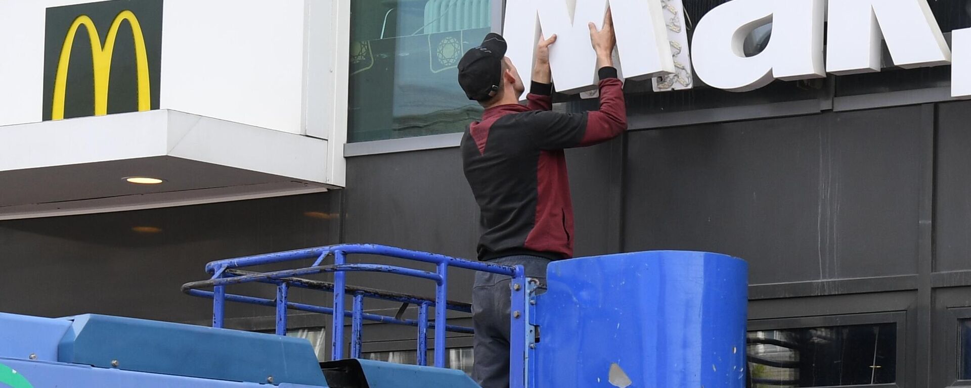 Un empleado desmonta un cartel del restaurante de comida rápida McDonald's de la fachada del centro comercial de la ciudad rusa de Novosibirsk  - Sputnik Mundo, 1920, 28.03.2024