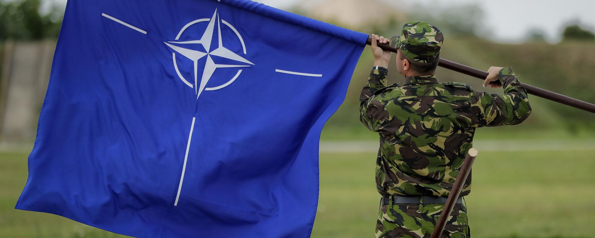 Un militar rumano enarbola la bandera de la OTAN tras la visita del ministro de Defensa británico, Michael Fallon, a una base aérea en Rumania, el 14 de junio de 2017 Un militar rumano enarbola la bandera de la OTAN tras la visita del ministro de Defensa británico, Michael Fallon, a una base aérea en Rumania, el 14 de junio de 2017 - Sputnik Mundo, 1920, 09.05.2024
