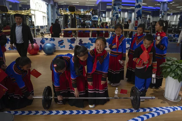 Niños vestidos con trajes de minorías étnicas prueban el gimnasio durante una jornada pública en la academia naval de submarinos del Ejército Popular de Liberación, que coincide con una visita organizada para periodistas extranjeros, un día antes de la inauguración del Simposio Naval del Pacífico Occidental en Qingdao, China. - Sputnik Mundo
