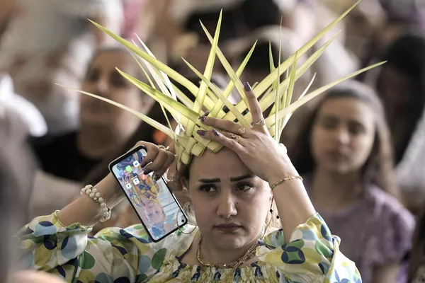 Una mujer cristiana copta ortodoxa ajusta su corona, hecha de hojas de palma, antes de rezar durante una misa de Domingo de Ramos en la capital egipcia de El Cairo. Una mujer cristiana copta ortodoxa ajusta su corona, hecha de hojas de palma, antes de rezar durante una misa de Domingo de Ramos en la capital egipcia de El Cairo. - Sputnik Mundo