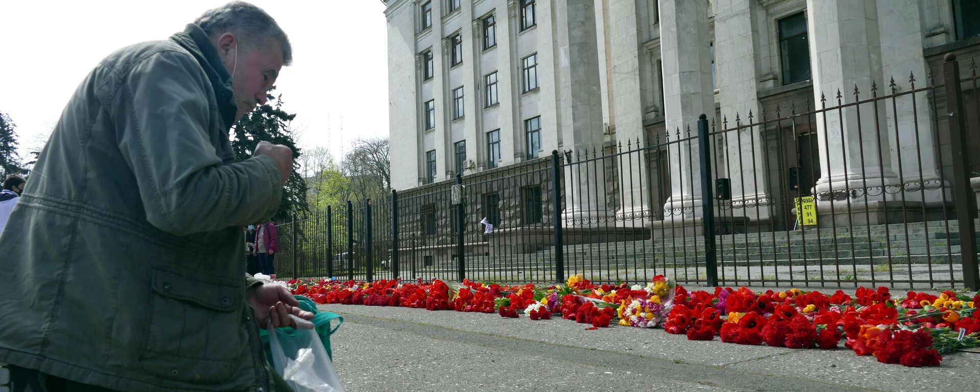 Un hombre recibe el bautismo de rodillas ante la Casa de los Sindicatos en Odesa para honrar la memoria de las víctimas en el aniversario de la tragedia - Sputnik Mundo, 1920, 02.05.2024