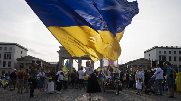 Una mujer ondea una enorme bandera ucraniana durante la manifestación para conmemorar el 32 aniversario de la independencia de Ucrania en Berlín, Alemania, el 24 de agosto de 2023 - Sputnik Mundo