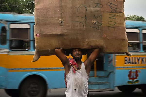 Un jornalero llevando un saco de cajas para cargarlas en un autobús, en Calcuta, la India. Un jornalero llevando un saco de cajas para cargarlas en un autobús, en Calcuta, la India. - Sputnik Mundo