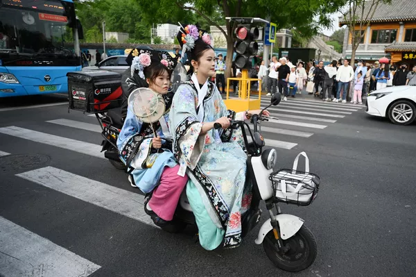 Dos mujeres vestidas con ropa tradicional montando un scooter eléctrico en una calle de Pekín. Dos mujeres vestidas con ropa tradicional montando un scooter eléctrico en una calle de Pekín. - Sputnik Mundo