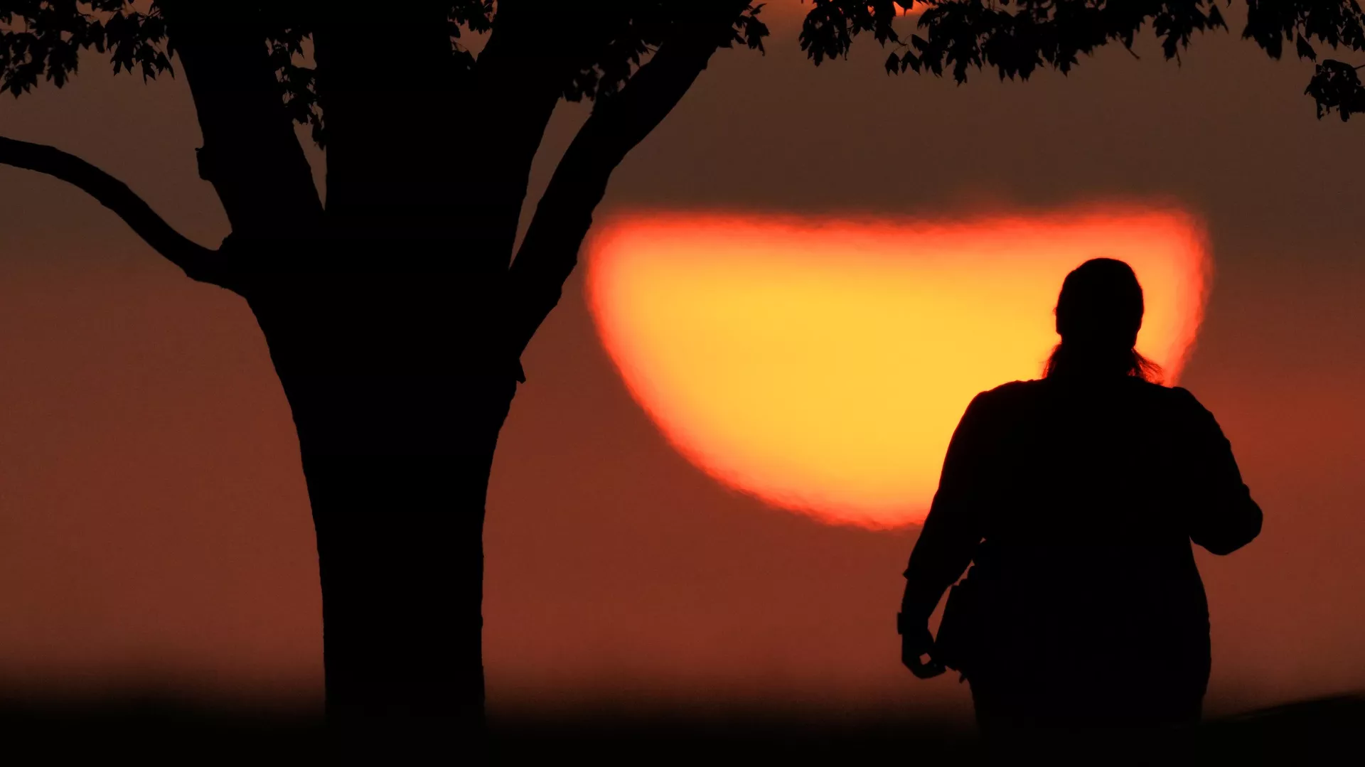 Una mujer observando la puesta de sol en un día caluroso, el 20 de agosto de 2023, en Kansas City, Missouri. Un nuevo estudio publicado el martes 14 de mayo de 2024 encuentra que el verano de 2023 fue el más caluroso en el hemisferio norte en más más de 2.000 años. (Foto AP/Charlie Riedel, archivo)
