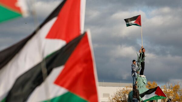 Un manifestante ondea la bandera palestina mientras se encuentra en la Fuente de Neptuno durante una protesta en apoyo a los palestinos bajo el lema 'Palestina libre' en Berlín, Alemania, el 4 de noviembre de 2023  - Sputnik Mundo