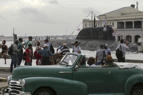 Una flotilla de la Armada de Rusia inicia su visita a Cuba con el ingreso a la bahía de La Habana y permanecerá en la capital del país caribeño hasta el 17 de junio.En la foto: un automóvil descapotable estadounidense pasa junto a personas que observan la llegada del submarino nuclear ruso Kazan al puerto de La Habana. - Sputnik Mundo