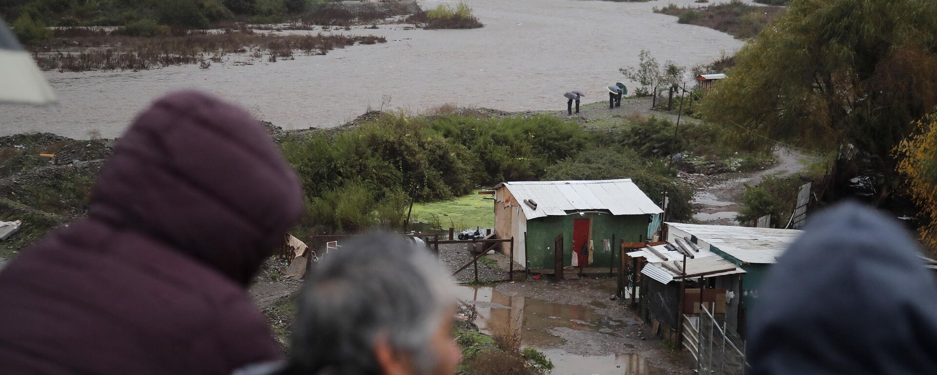 Habitantes miran el río Mapocho tras las fuertes lluvias en la comuna de Talagante, Santiago, el 13 de junio de 2024.  - Sputnik Mundo, 1920, 22.06.2024