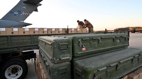 Militares ucranianos cargan un camión de plataforma con cajas mientras se apilan misiles estadounidenses FIM-92 Stinger (frente) y un sistema portátil de defensa antiaérea (Manpads) tras ser enviados al aeropuerto de Boryspil, en Kiev, el 13 de febrero de 2022 - Sputnik Mundo