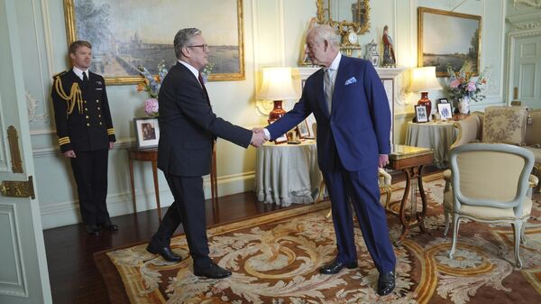 El rey Carlos III del Reino Unido, a la derecha, estrecha la mano de Keir Starmer cuando invitó al líder del Partido Laborista a convertirse en primer ministro y a formar un nuevo Gobierno, tras la aplastante victoria del Partido Laborista en las elecciones generales anticipadas, el 5 de julio, 2024 - Sputnik Mundo