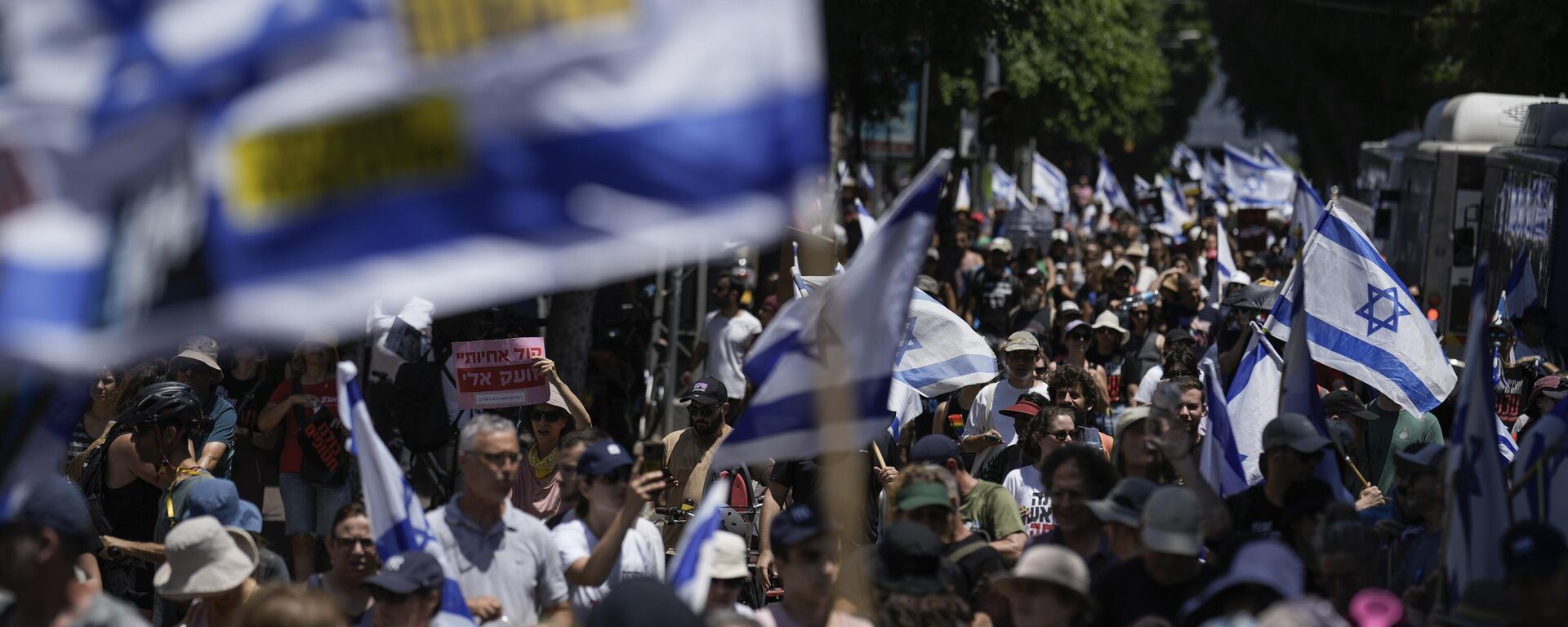 Manifestantes marchan con banderas israelíes durante una protesta para conmemorar los nueve meses transcurridos desde el comienzo del conflicto palestino-israelí y pedir la liberación de los rehenes retenidos en la Franja de Gaza por el movimiento Hamás, el 7 de julio, 2024 - Sputnik Mundo, 1920, 12.07.2024