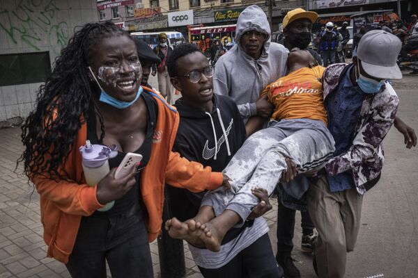 La Policía de Kenia lanzó gases lacrimógenos para disolver las protestas, en las que los manifestantes pedían la dimisión del presidente.En la foto: personas transportando a una mujer inconsciente durante una protesta en la capital del país, Nairobi. - Sputnik Mundo