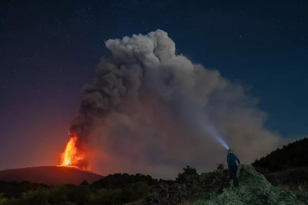 Una persona observando las nubes y la lava sobre el volcán Etna durante una erupción en la isla italiana de Sicilia. Una persona observando las nubes y la lava sobre el volcán Etna durante una erupción en la isla italiana de Sicilia. - Sputnik Mundo