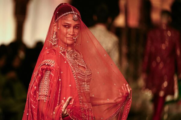 El emblemático dúo Abu Jani y Sandeep Khosla encabezó el desfile inaugural con sus marcas Asal y Mard, que combinan tejidos y bordados tradicionales con diseños modernos.En la foto: una modelo presenta una creación de los diseñadores Abu Jani y Sandeep Khosla. - Sputnik Mundo