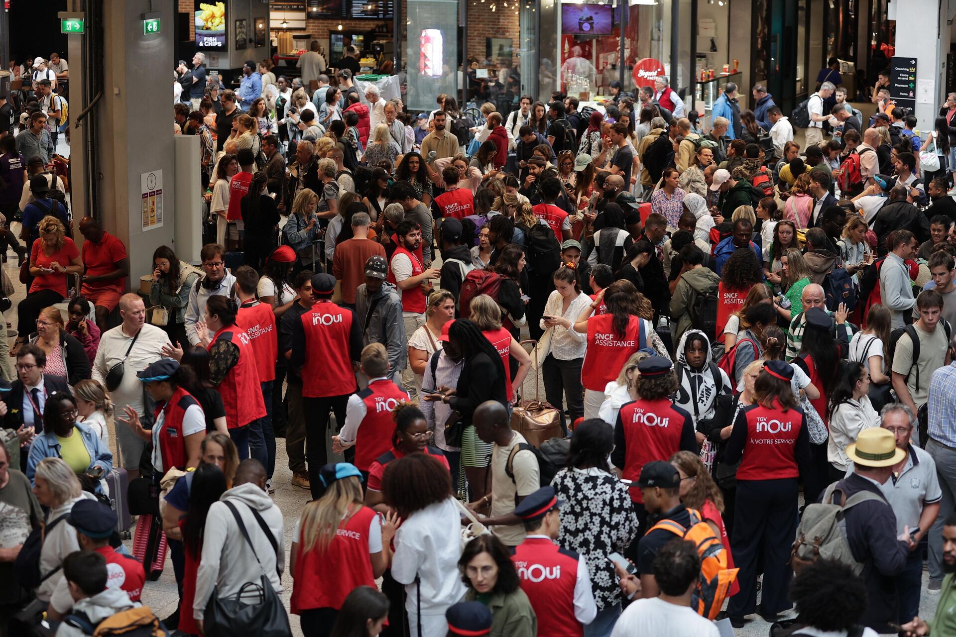 Los empleados de la compañía ferroviaria SNCF hablan con los pasajeros que esperan la salida de sus trenes en la estación de tren Gare Montparnasse en París el 26 de julio de 2024, luego de que la red ferroviaria de alta velocidad de Francia se vio afectada por un sabotaje que interrumpió el sistema de transporte horas antes de la ceremonia de apertura de los Juegos Olímpicos París 2024.  - Sputnik Mundo, 1920, 26.07.2024