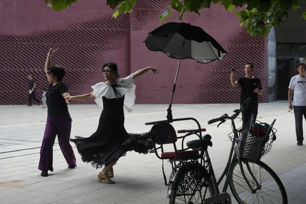 Unas mujeres participan en una danza, en Pekín, China. El baile callejero es popular entre las mujeres chinas de mediana edad y mayores. Bailar en plazas y parques ayuda a muchos hombres y mujeres mayores de China a mantenerse en forma y sirve para socializarse. - Sputnik Mundo