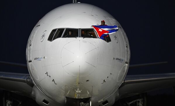 El luchador cubano Mijaín López Núñez, cinco veces campeón olímpico, ondea una bandera cubana desde la ventanilla del piloto de un avión a su llegada al aeropuerto José Martí de La Habana, Cuba. - Sputnik Mundo