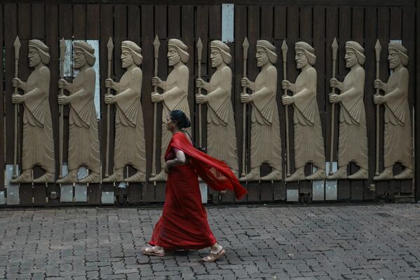 Una mujer pasa junto a un relieve que representa a los primeros zoroastrianos en una colonia parsi durante el festival Navroze, el Año Nuevo parsi, en Bombay, la India. - Sputnik Mundo