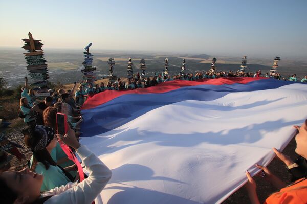 La bandera rusa, con una superficie de 108 metros cuadrados, fue desplegada en la montaña Mashuk de Piatigorsk para celebrar el Día de la Bandera Nacional. - Sputnik Mundo