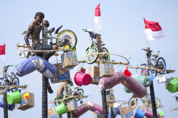 Un hombre tomando parte en la competición de escalada en poste engrasado durante las celebraciones del Día de la Independencia en la capital indonesia de Yakarta. - Sputnik Mundo