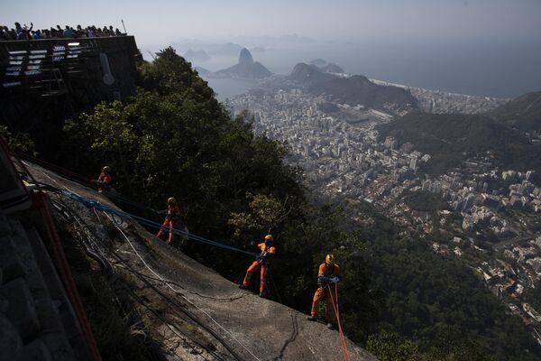 Trabajadores descienden en rappel por una cuerda desde el cerro de Corcovado para retirar la basura amontonada a los pies de la estatua del Cristo Redentor en la ciudad brasileña de Río de Janeiro. - Sputnik Mundo