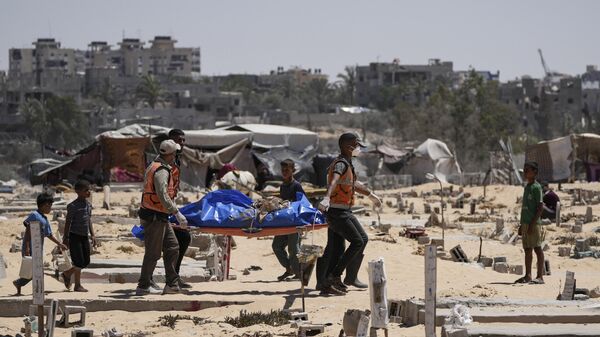 Trabajadores transportan un cadáver, uno de los más de 80 cuerpos devueltos por Israel, a un cementerio en Jan Yunis, Franja de Gaza, 5 de agosto de 2024 - Sputnik Mundo