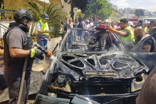 Agentes de defensa civil inspeccionan los restos de un automóvil incendiado por un ataque israelí en la ciudad libanesa de Sidón. - Sputnik Mundo