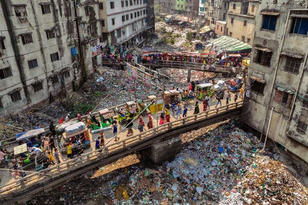 Canal de la basura, tomada por Mushfiqul Alam, de Bangladesh, recibió calificación especial del jurado.La obra muestra a la gente que está cruzando puentes sobre el antaño limpio canal.Dhaka recoge 646 toneladas de plástico al día, lo que afecta gravemente al río Buriganga, que en su tiempo era la savia de la ciudad. - Sputnik Mundo