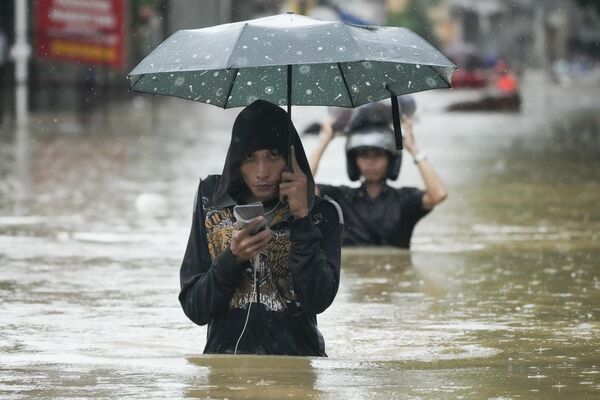 Un residente de la ciudad filipina de Cainta atraviesa una calle inundada. - Sputnik Mundo