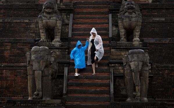 Una turista con su hijo descienden por las escaleras de un templo en la ciudad nepalí de Bhaktapur. - Sputnik Mundo