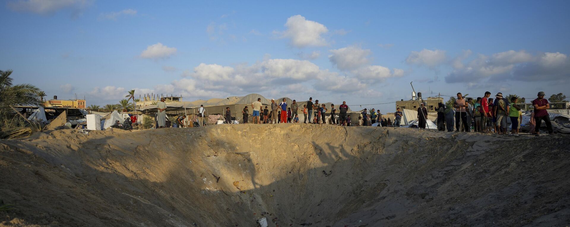 Ciudadanos palestinos observan la destrucción de un campamento de refugiados desplazados por la guerra en la Franja de Gaza después de un ataque aéreo israelí este martes 10 de septiembre, en el que asesinó al menos a 40 personas.  - Sputnik Mundo, 1920, 10.09.2024