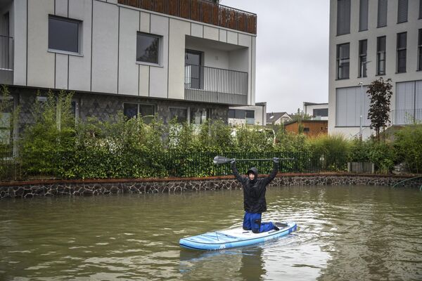 Un hombre utiliza una tabla de surf durante una inundación en Zahorska Bystrica, Eslovaquia. - Sputnik Mundo