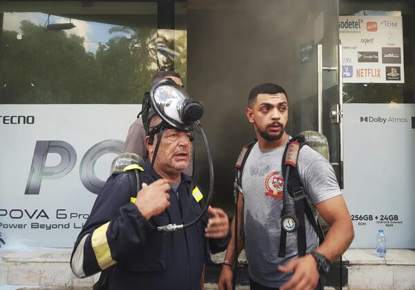 Bomberos se encuentran afuera de una tienda de telefonía móvil dañada después la explosión de walkie-talkies en su interior, en la ciudad portuaria sureña de Sidón, el Líbano. - Sputnik Mundo