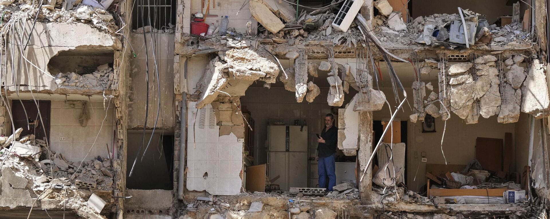 Un hombre observa a los rescatistas revisar los escombros mientras buscan personas aún desaparecidas en el lugar del ataque israelí del viernes en los suburbios del sur de Beirut, el lunes 23 de septiembre de 2024. (Foto AP/Hassan Ammar) - Sputnik Mundo, 1920, 27.09.2024