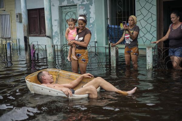 Un hombre flota en un contenedor en una calle inundada por el paso del huracán Helene, en Batabano, provincia de Mayabeque, Cuba. - Sputnik Mundo