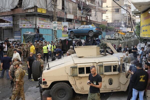 Una carretilla elevadora retira un coche dañado mientras el Ejército libanés y los trabajadores de emergencias se reúnen en el lugar de un ataque aéreo israelí en los suburbios del sur de Beirut. - Sputnik Mundo