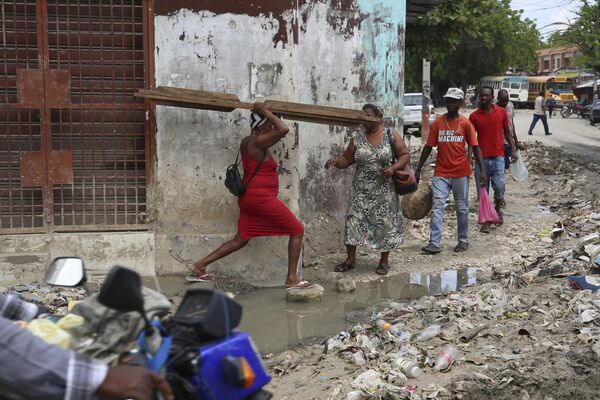 Peatones cruzan un charco de agua en el centro de Puerto Príncipe, Haití. - Sputnik Mundo