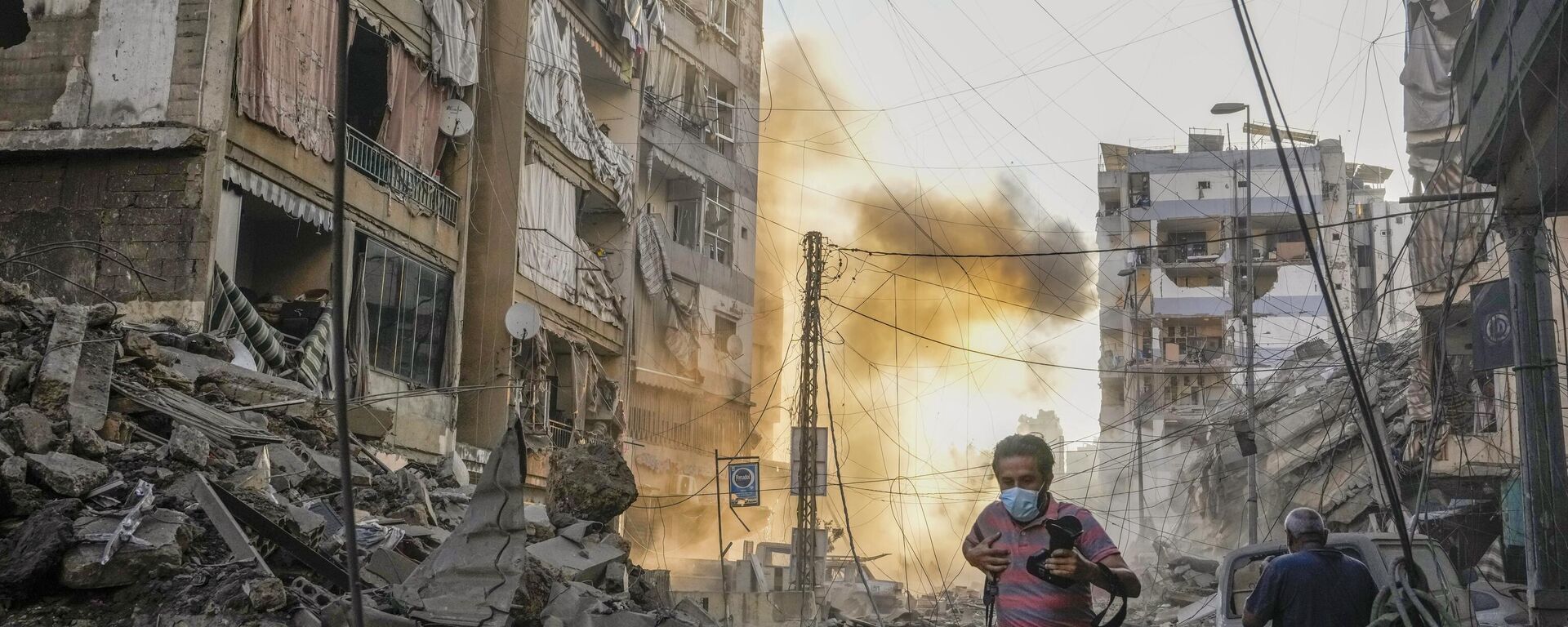 Un fotógrafo corre para cubrirse mientras se levanta humo en el fondo después de un ataque aéreo israelí en Dahiyeh, Beirut, Líbano, el viernes 4 de octubre de 2024. (Foto AP/Hassan Ammar) - Sputnik Mundo, 1920, 05.10.2024