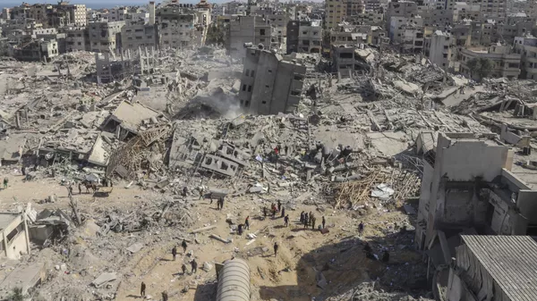 Un grupo de palestinos camina entre la destrucción dejada por la ofensiva aérea y terrestre israelí en la Franja de Gaza cerca del hospital Shifa en la ciudad de Gaza (archivo) - Sputnik Mundo